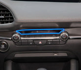Modern car dashboard close-up showing black leather trim, LED accents, and climate control dials