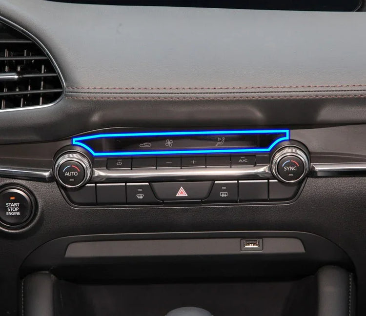 Modern car dashboard close-up showing black leather trim, LED accents, and climate control dials