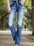 Woman wearing high-waisted blue flared jeans with white contrast stitching outdoors