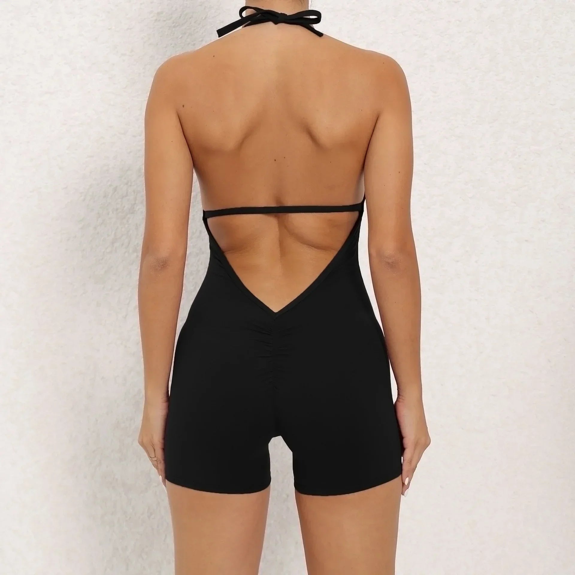 Backless black halter romper with fitted stretchy material and ruched seam detail
