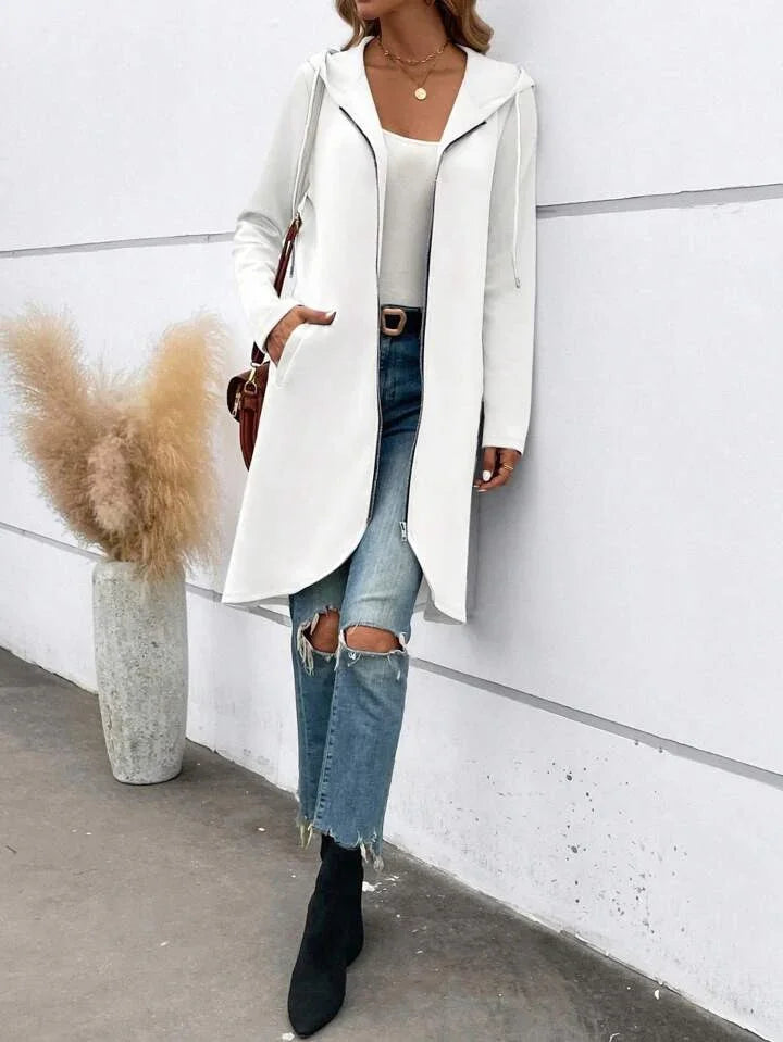 Woman wearing a white hooded coat, light tank top, ripped blue jeans, and black boots