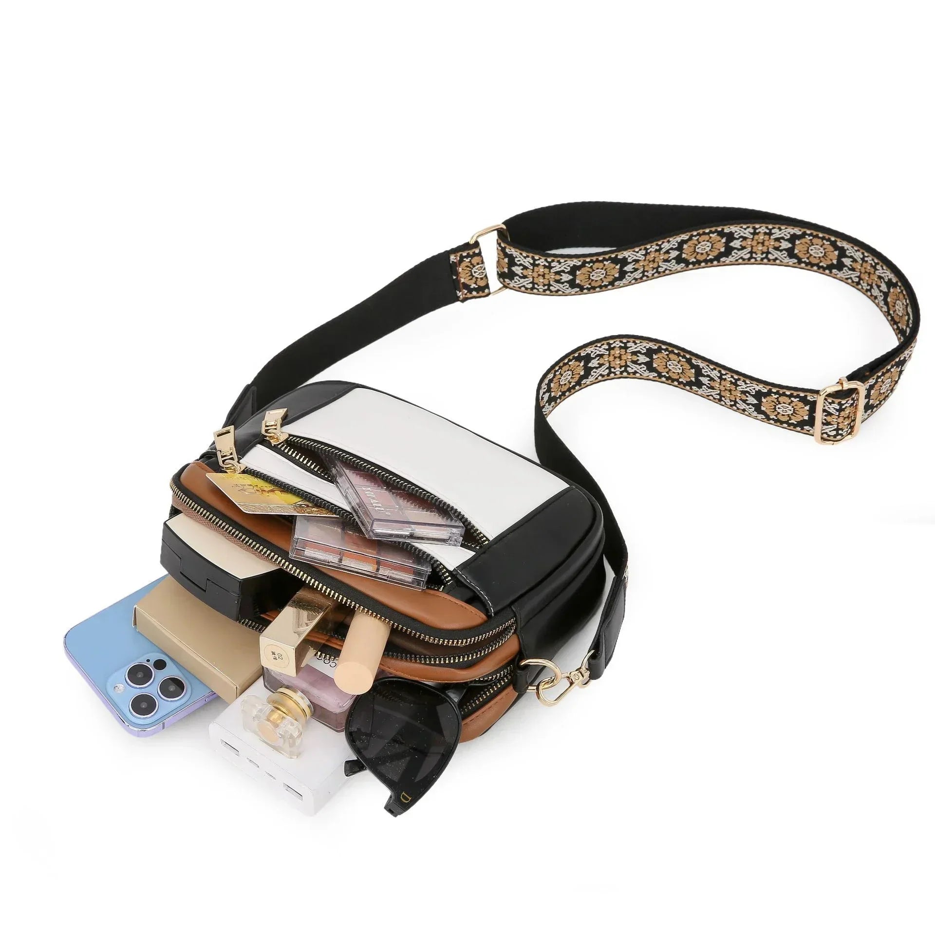 Clear and black crossbody bag with wide floral strap, filled with everyday essentials