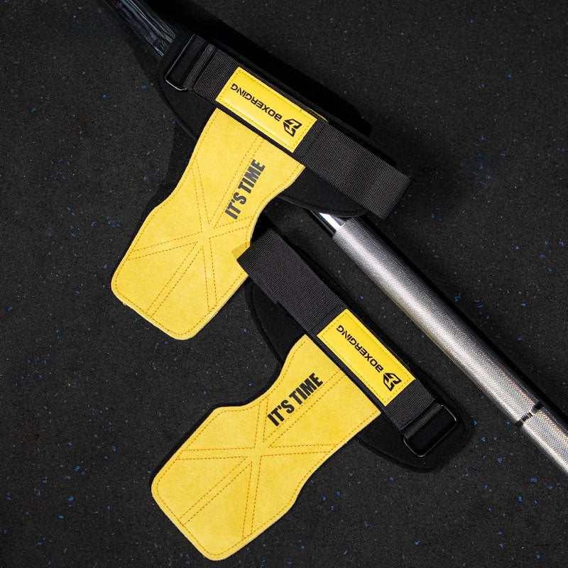 Yellow suede weightlifting wrist straps with black adjustable bands on gym floor