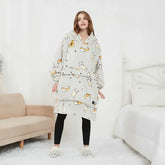 Woman wearing oversized grey hooded fleece blanket with cat print, relaxed fit loungewear.