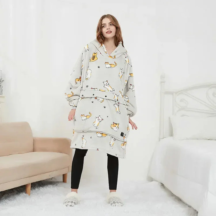 Woman wearing oversized grey hooded fleece blanket with cat print, relaxed fit loungewear.