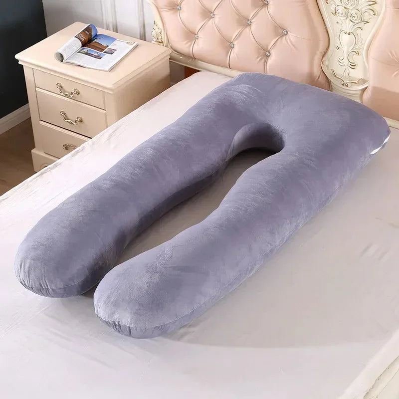 Gray U-shaped plush body pillow with soft, velvety texture on a bed