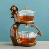 Elegant glass teapot set with sculpted wood-look holder and amber tea, modern kitchen decor