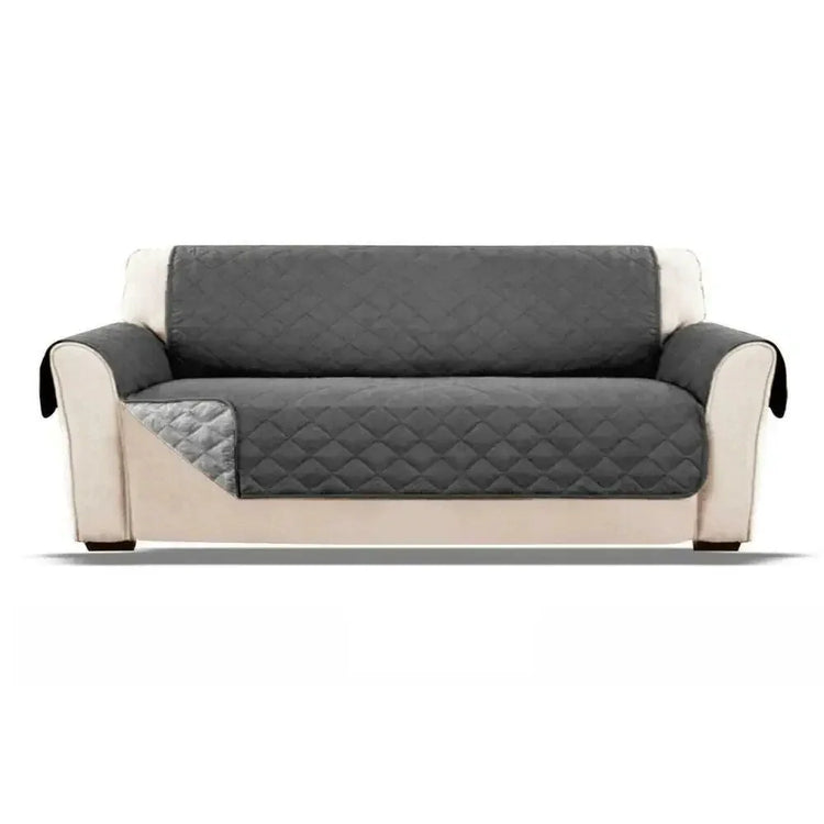 Beige sofa with a fitted dark gray quilted protective cover, modern minimalist style