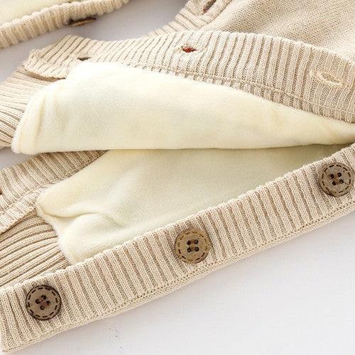 Close-up of beige knit cardigan with soft fleece lining, ribbed cuffs, and button details