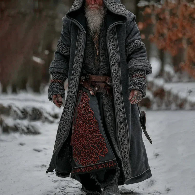 Man in a dark, long, hooded wool coat with intricate patterns and layered winter streetwear