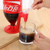 Soda dispenser stand with red faucet pouring cola into a clear glass mug on wood table