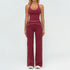 Woman wearing burgundy fitted halter jumpsuit with white piping, flared legs, stretchy material