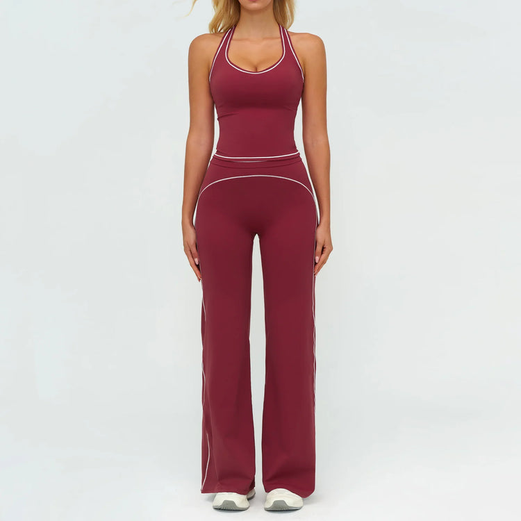 Woman wearing burgundy fitted halter jumpsuit with white piping, flared legs, stretchy material