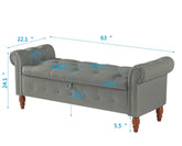 Gray upholstered bench with tufted seat, rolled arms, wooden legs, and size measurements.