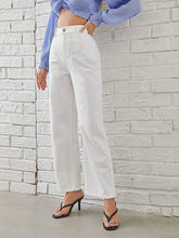 Woman wearing high-waisted white straight-leg jeans and black heeled sandals