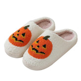 White fuzzy slippers with orange pumpkin design, soft cozy material, closed-back style