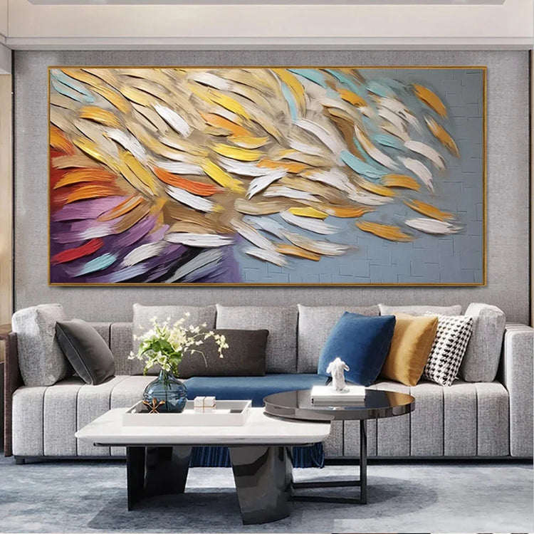 Modern living room with light gray sectional sofa, colorful abstract wall art, and velvet throw pillows.