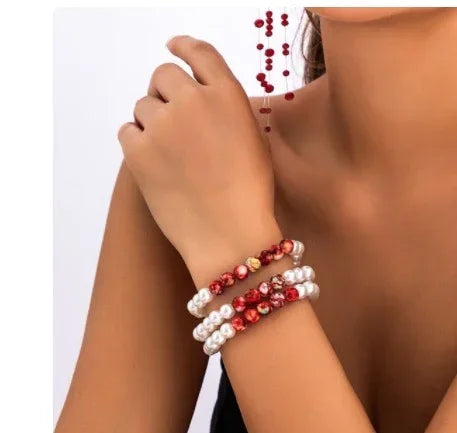 Woman wearing stacked pearl and red bead bracelets, modern jewelry style, close fit