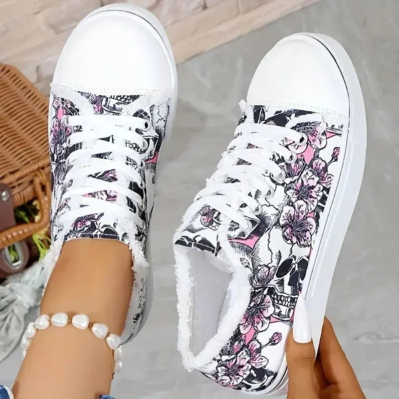 White low-top sneakers with black skull and pink floral print, lace-up, casual streetwear style