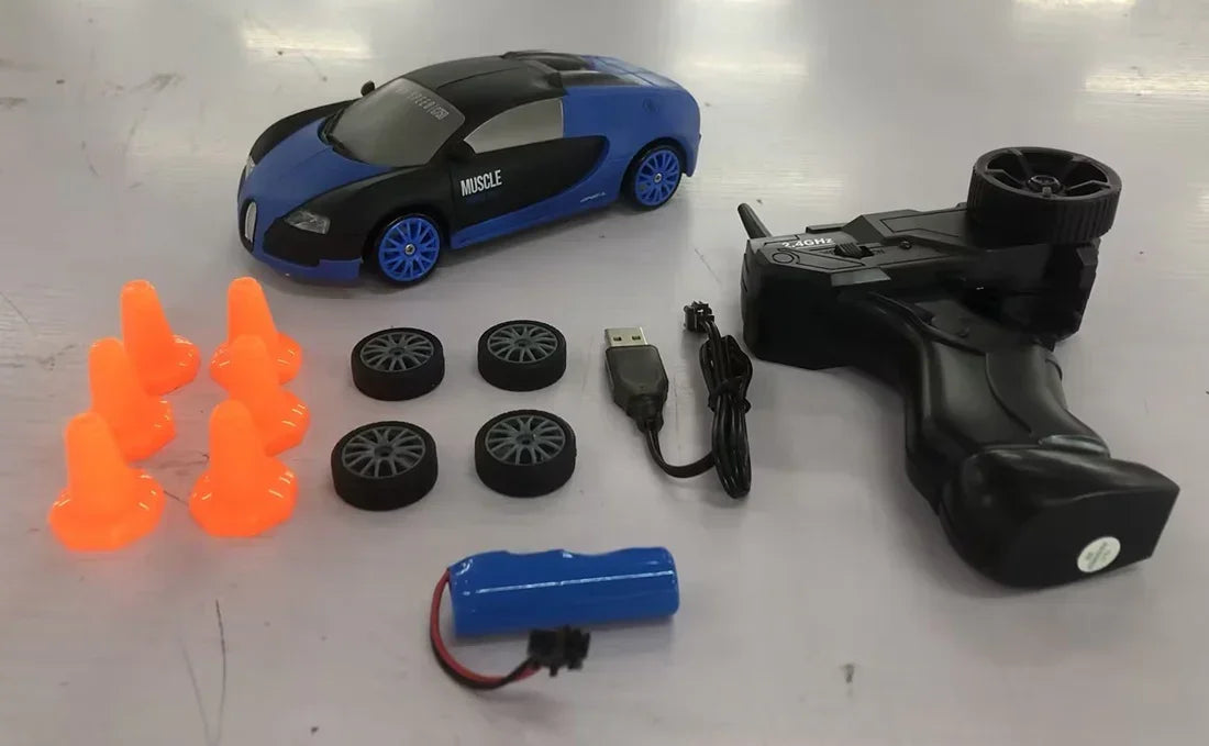 Black and blue remote control toy car set with extra wheels, six orange cones, USB cable, controller, and battery.