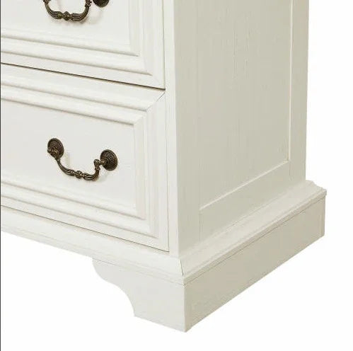 Close-up of white wooden dresser with ornate bronze drawer handles, classic style