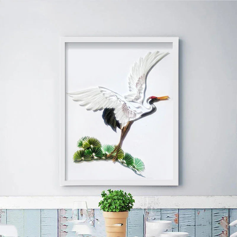 Framed artwork of a white crane with black wingtips above green leaves on a white wall