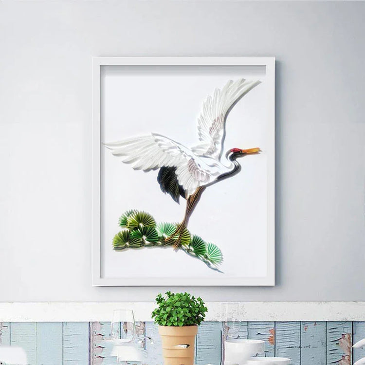 Framed artwork of a white crane with black wingtips above green leaves on a white wall