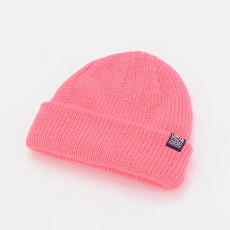Bright pink ribbed knit beanie with folded brim, soft acrylic material, relaxed fit