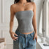 Woman wearing a fitted gray striped strapless tube top and relaxed blue jeans indoors