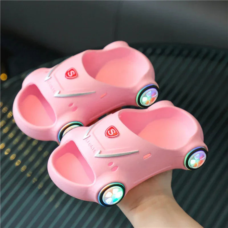 Pink car-shaped slippers with open toe, soft foam material, and colorful wheel accents