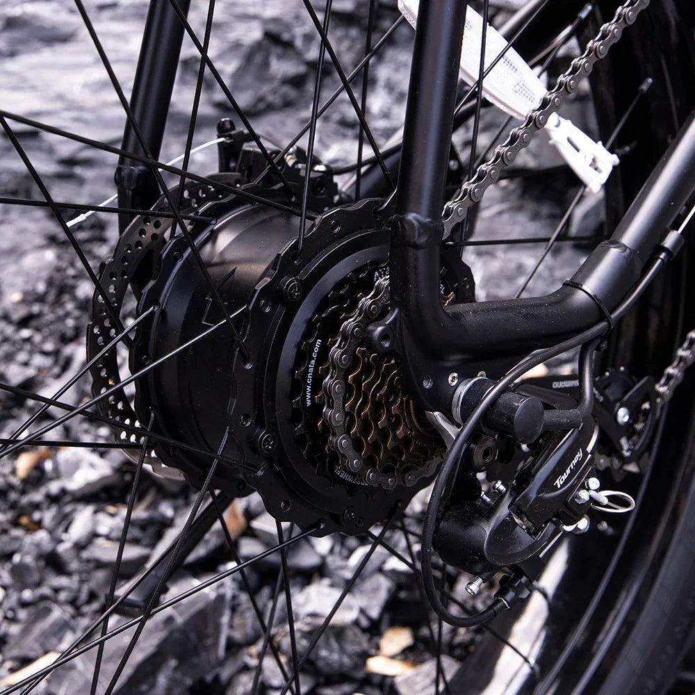 Close-up of black bicycle rear wheel with gear cassette, derailleur, and disc brake