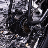 Close-up of black bicycle rear wheel with gear cassette, derailleur, and disc brake
