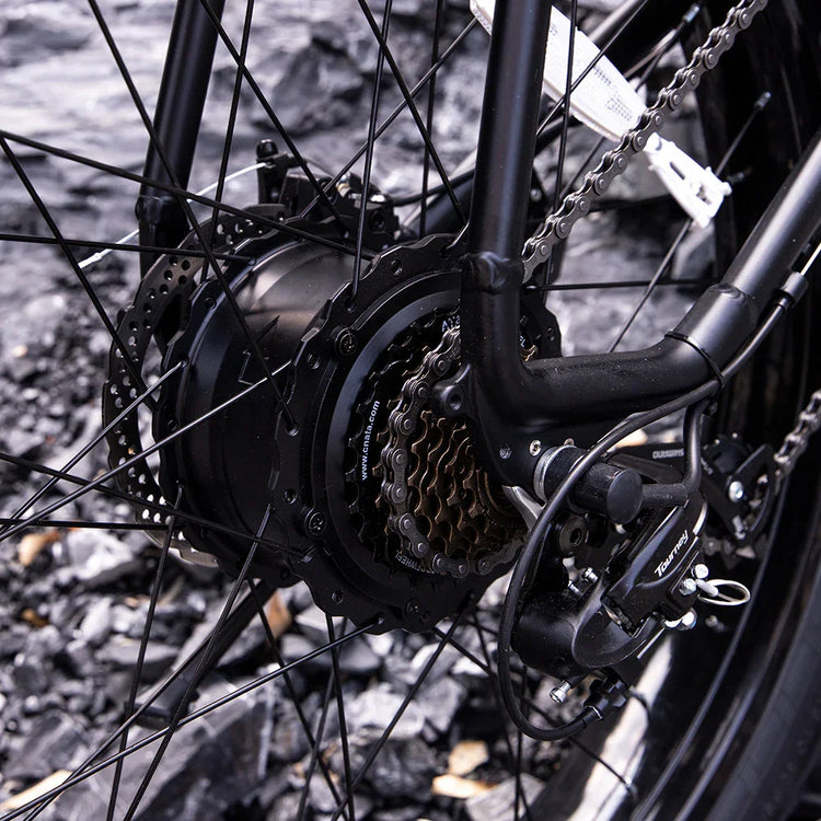 Close-up of black bicycle rear wheel with gear cassette, derailleur, and disc brake
