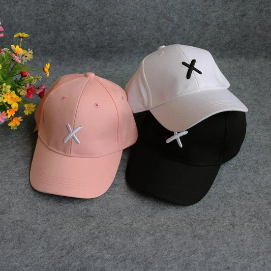 Three baseball caps in pink, white, and black with minimalist X embroidery, cotton material, casual fit.