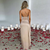 Woman in beige satin backless gown with slim fit, rose petals and candles on floor