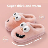 Plush pink fuzzy slippers with cartoon eyes and smiling face, thick warm cozy fit.