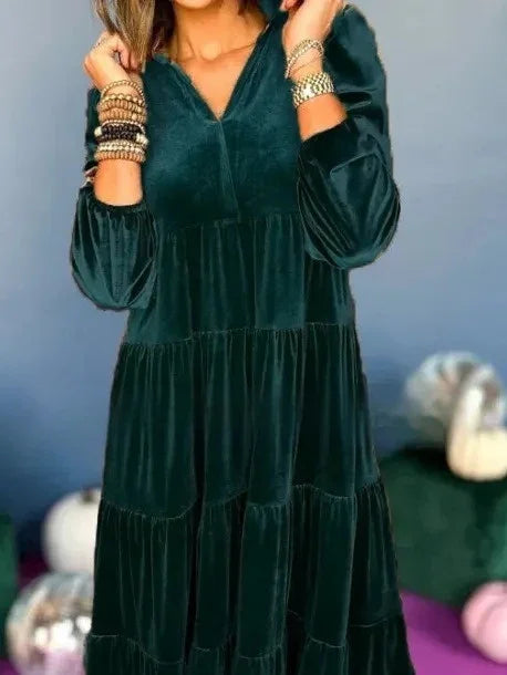 Woman wearing a dark green velvet tiered long-sleeve dress with relaxed fit