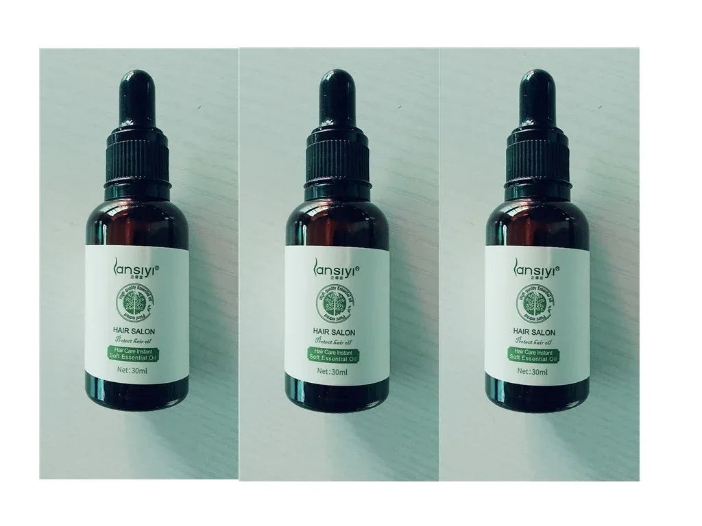Three amber glass dropper bottles of hair care essential oil on light surface