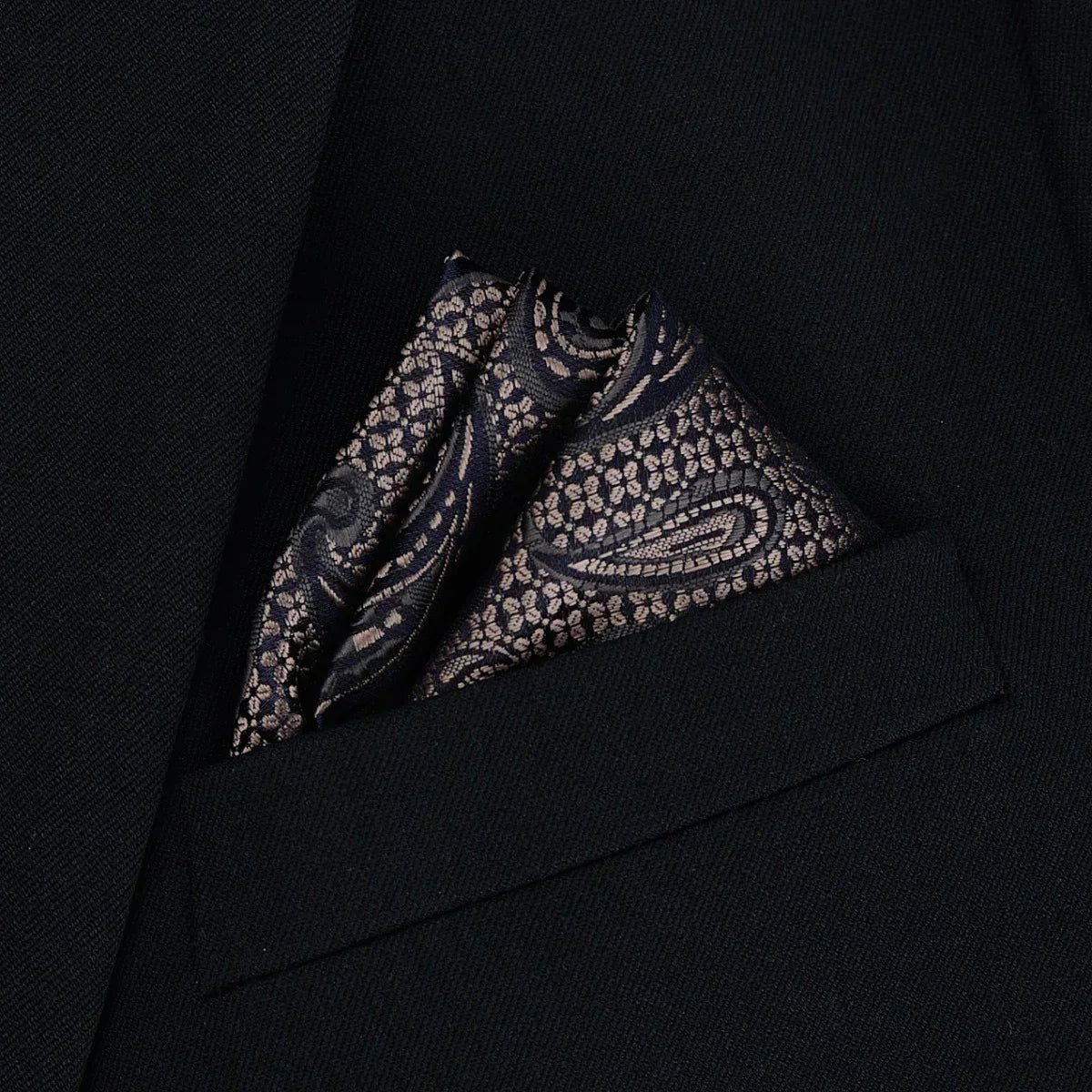 Black suit jacket with a folded paisley silk pocket square in gold and navy tones