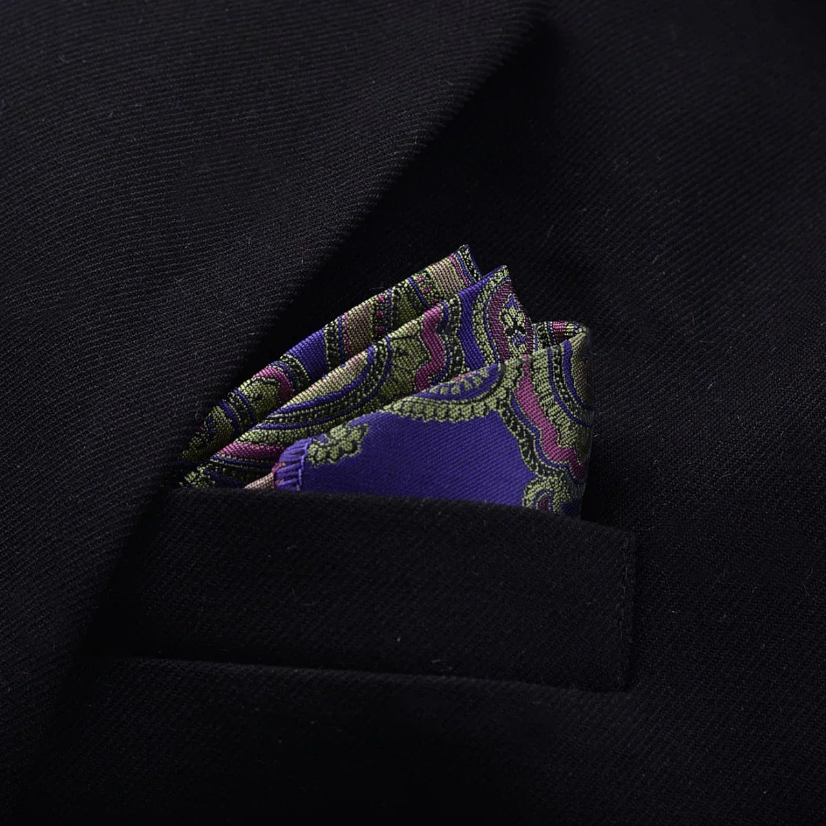 Black suit jacket with a purple and green paisley silk pocket square