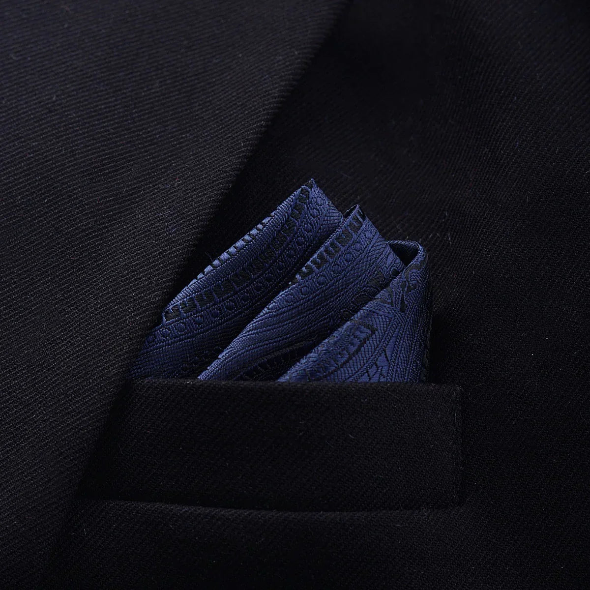 Close-up of a dark textured blazer with a blue patterned silk pocket square