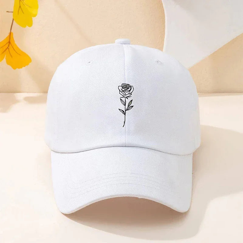 White cotton baseball cap with black embroidered rose, minimalist streetwear style
