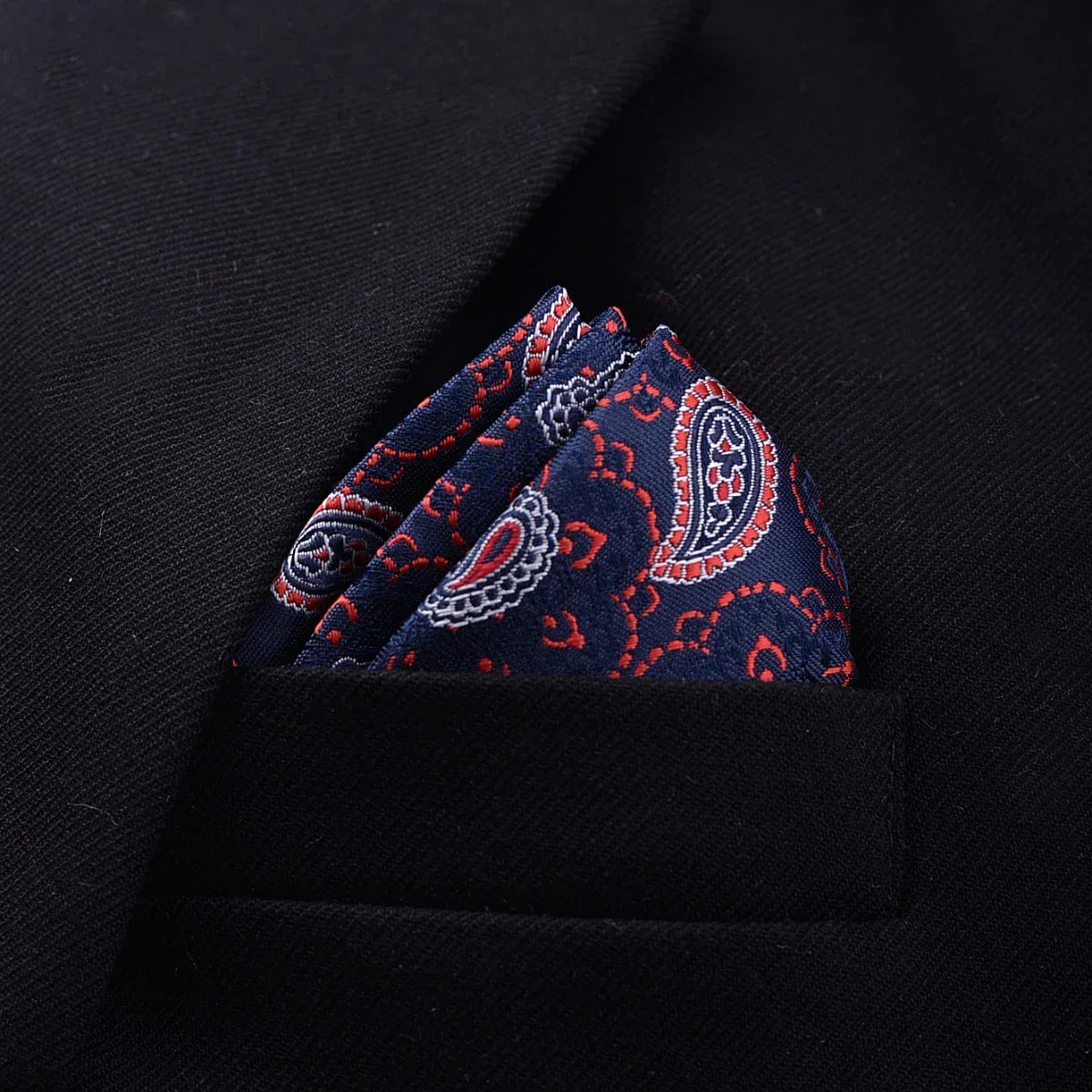 Navy blue paisley silk pocket square with red and white accents in black suit jacket