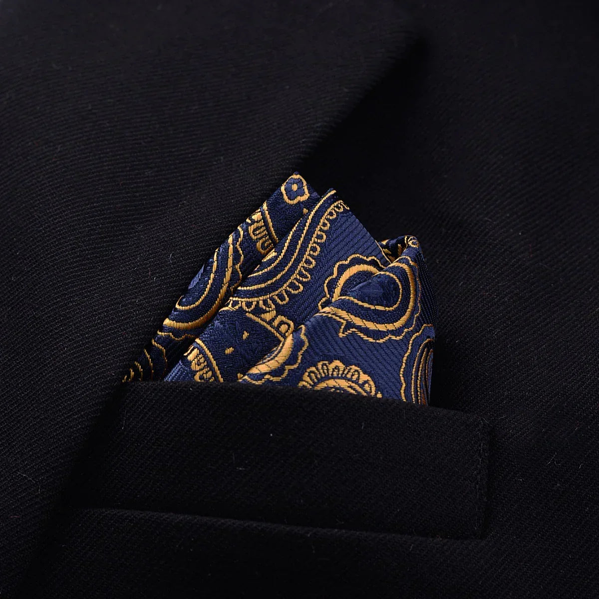 Navy blue and gold paisley pocket square in black suit jacket pocket, formal style