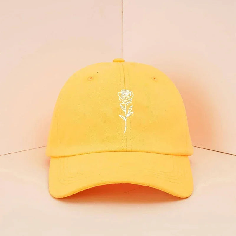 Yellow cotton baseball cap with white rose embroidery, casual streetwear style, relaxed fit.