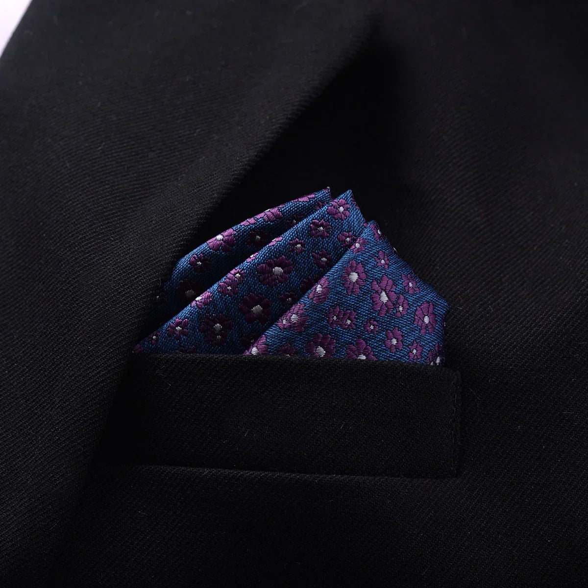 Black suit jacket with blue and purple floral pocket square, tailored fit.