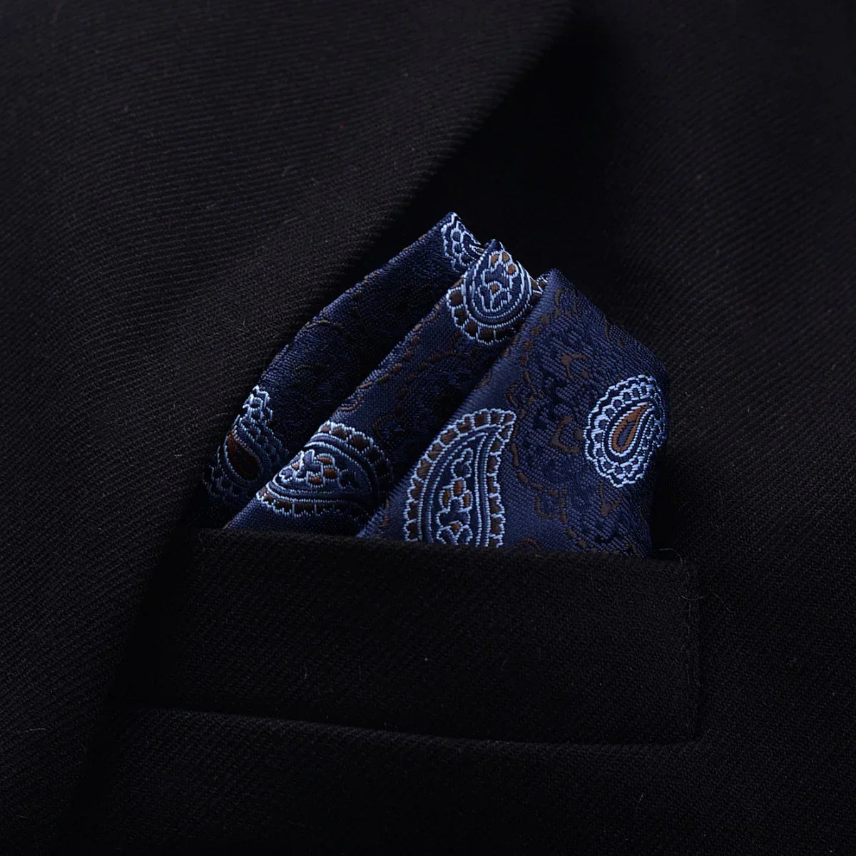 Dark blue paisley silk pocket square in black suit jacket pocket, classic formal style