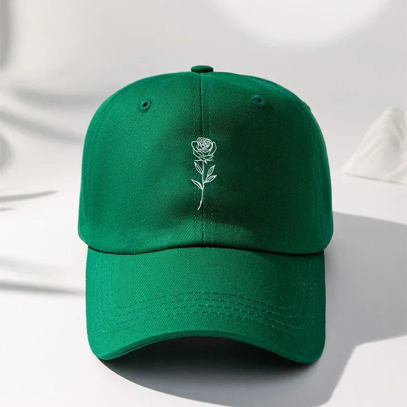 Green cotton baseball cap with white embroidered rose design, modern streetwear style