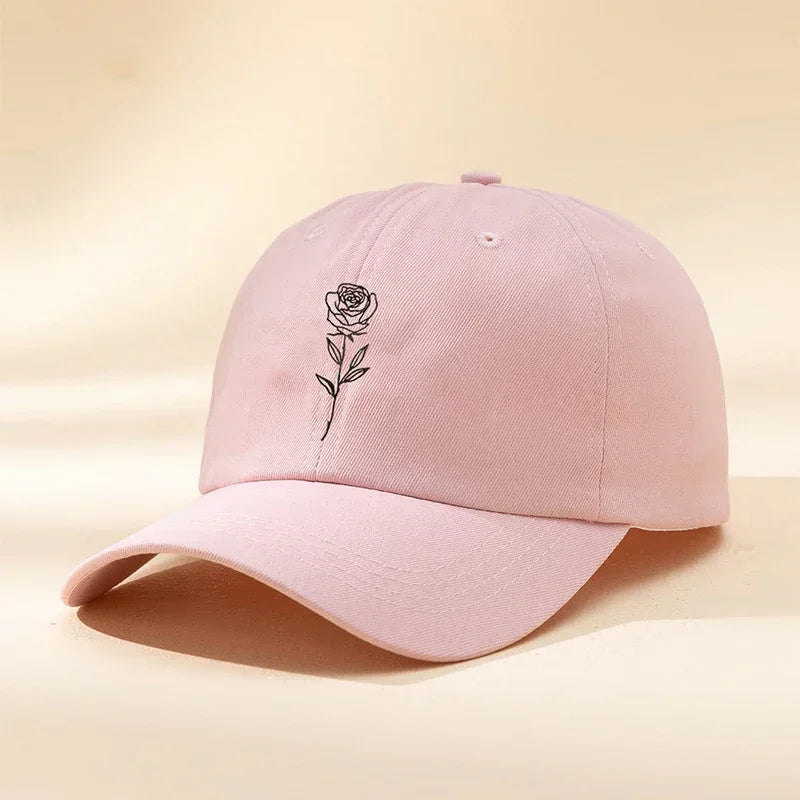 Light pink cotton baseball cap with embroidered black rose design, relaxed fit