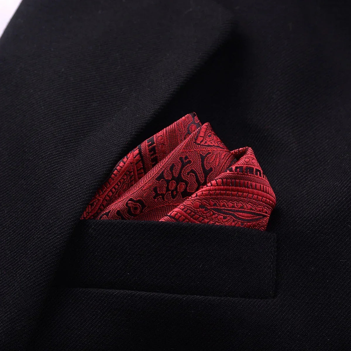 Black suit jacket with a red patterned silk pocket square, classic slim fit style